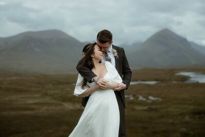 Couple share a kiss on a mountain during a snowy golden hour elopement in the Cairngorms, Scotland