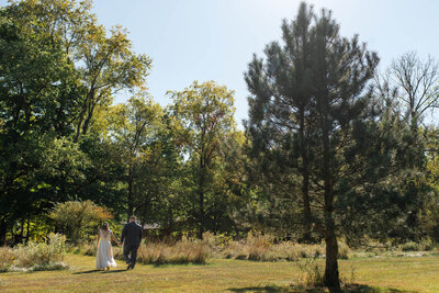 Bride and groom walk in meadow