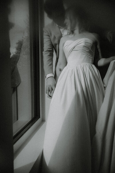 bride and groom lean against a wall at the pear tree estate during their wedding to create a dramatic black and white moody portrait