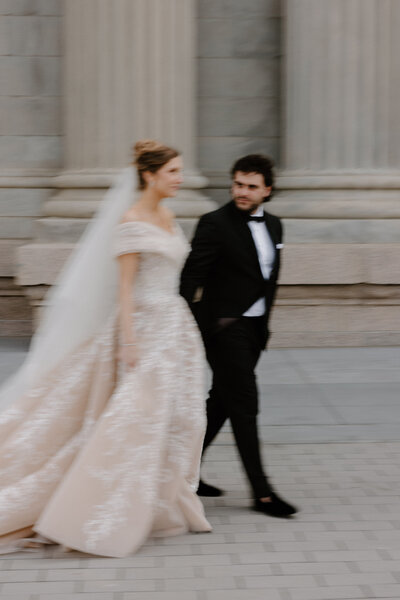 A slightly blurred image of a wedding couple walking together 