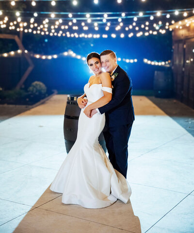 Bride and groom under twinkle lights on patio | Night Wedding Photo at The Hamilton Manor | Hamilton Township, New Jersey