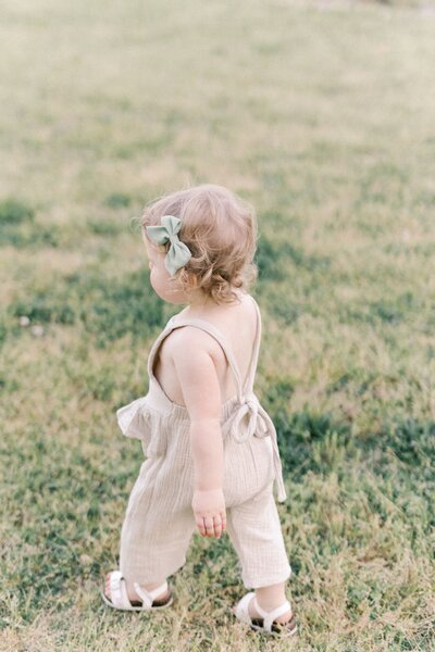 Little girl walks away on grass