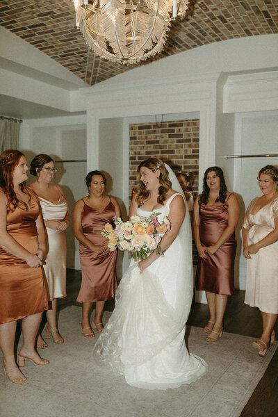 bride holding bridal bouquet surrounded by bridesmaids