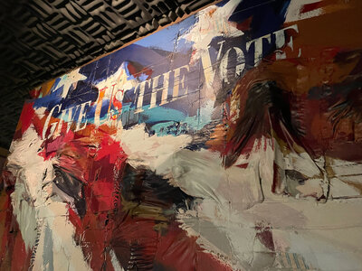 Flag mural with words "Give Us The Vote"