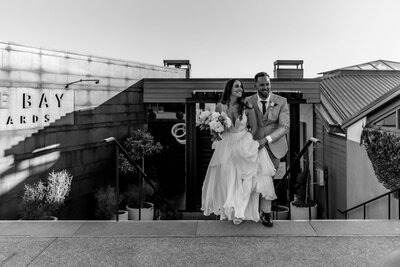 Bride and groom walking up the stairs at a rooftop wedding venue in Auckland, captured in a modern and romantic wedding portrait by Zanthe Vorsatz Photography.