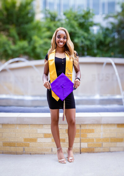 a high school senior posing with her graduation cap