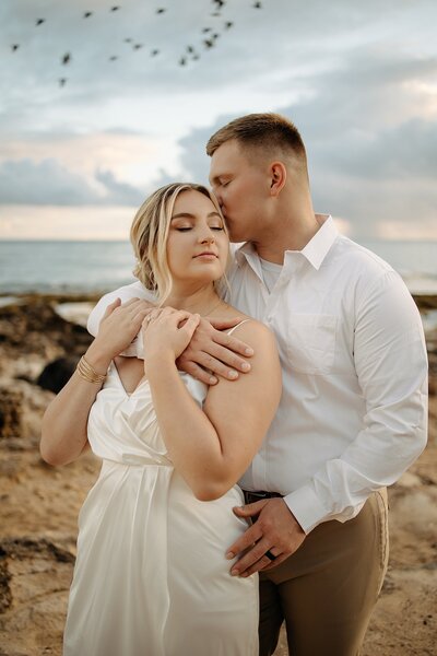 Couple snuggled together for their beach wedding