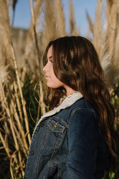 young girl standing with jean jacket and long brown hair