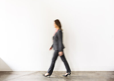 Lawyer walking in front of white wall during a photo session. 