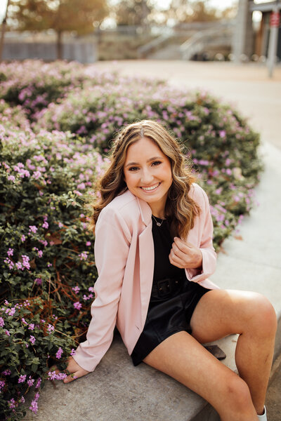Senior girl poses near flowers