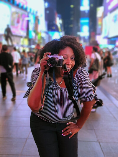 Portrait Photographer Erica Payne holding a camera in times square.