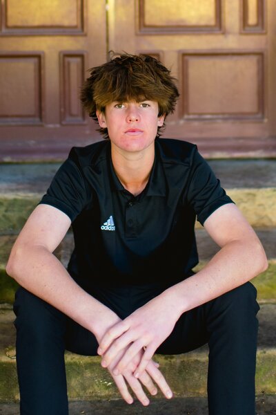 senior boy sitting on steps at the courthouse in santa barbara california