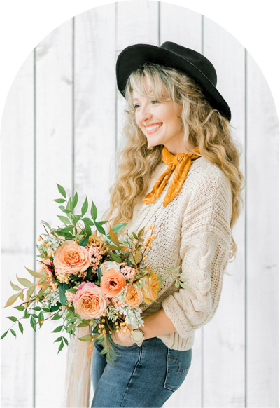 Headshot of Neva Michelle holding colorful bouquet and wearing a hat.