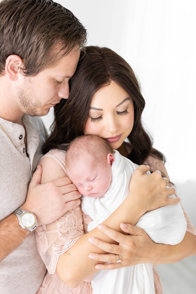 Parents embracing with newborn baby