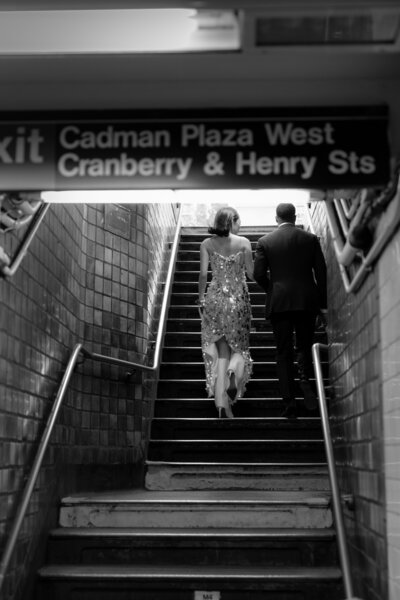 Bride and groom walking down subway stairs in New York City, blending timeless love with modern urban energy for their elopement.