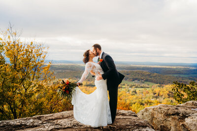 Text: Eloping couple sharing a kiss on rocky ridge with panoramic Virginia valley views