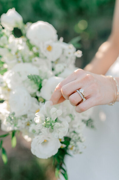Image of a bride's ring as she is picking through her white bridal bouquet.