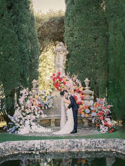 Couple kissing in front of ceremony flowers at their la Foce Wedding in val d' orcia, captured by renowned Tuscany photographer Andreas K. Georgiou