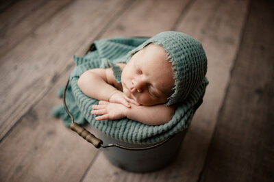 newborn sleeping with hands under head in bucket