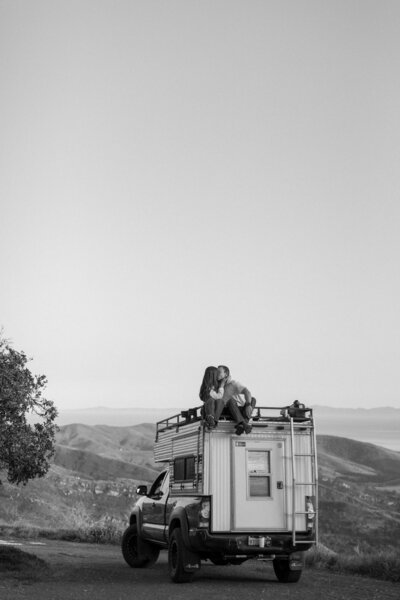 couple kisses on top of van