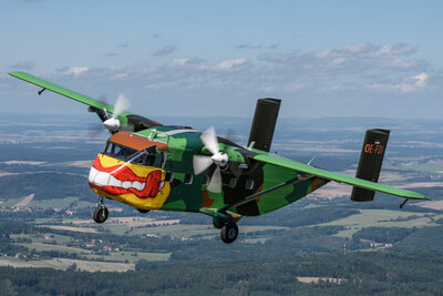 Die PInk Skyvan fliegt durch den blauen Himmel. Das Bild zeigt ihre einzigartige Lackierung