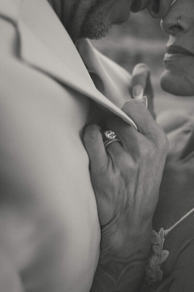 Close-up of bride’s hand showcasing a sparkling engagement ring as she holds onto the groom’s suit during an intimate elopement at Cathedral Rock in Sedona, Arizona.