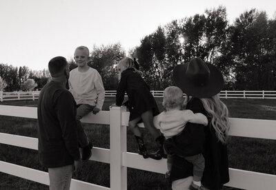 A family of 4 on a bridge, in a park in Rexburg, ID candidly smiling.