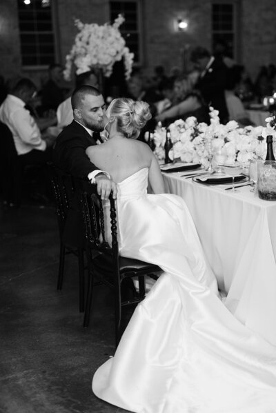 Bride and groom sit close together at a decorated reception table during their wedding at Grbic Events in St. Louis.