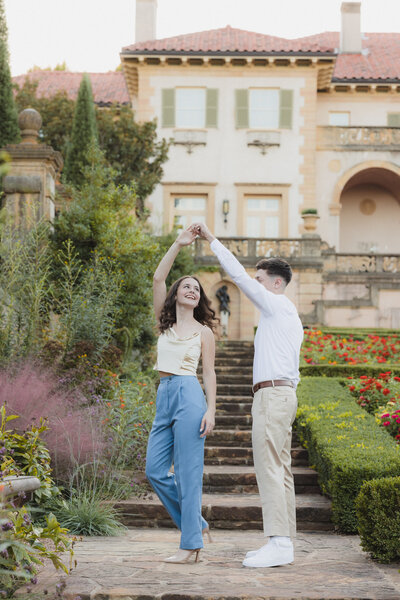 a man twirling his fiance in a garden
