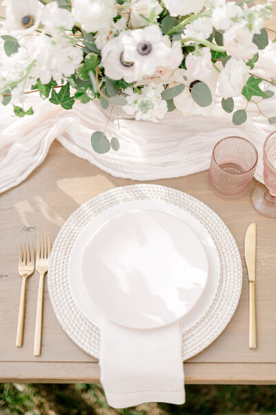 close up shot of a table setting with white plates and gold utensils