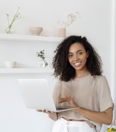 Medium-skin woman holding a laptop and smiling at camera