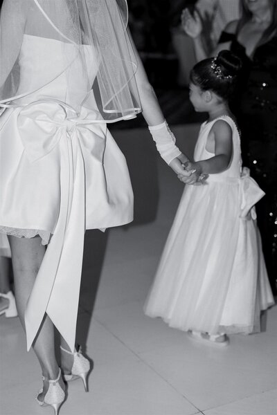 A newlywed holding the hand of a small child and walking with them 