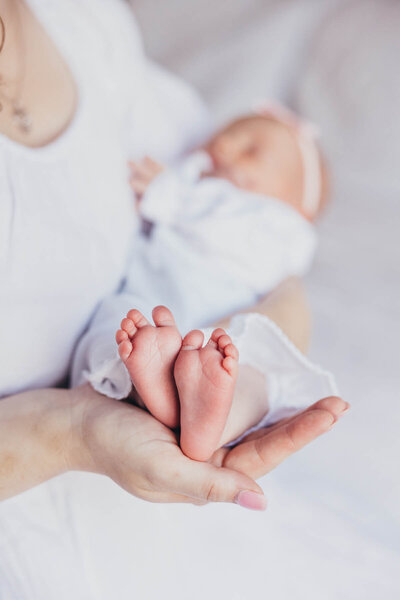 close up of sweet baby feet held in mom's hands during their newborn photoshoot in their San Diego home