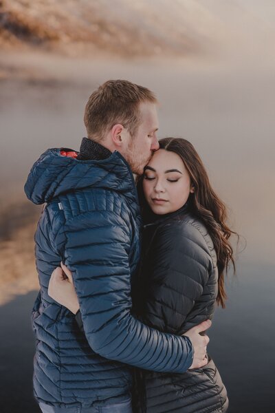 A couple hugs in the cold morning light at Kenai Lake, Cooper Landing, Alaska