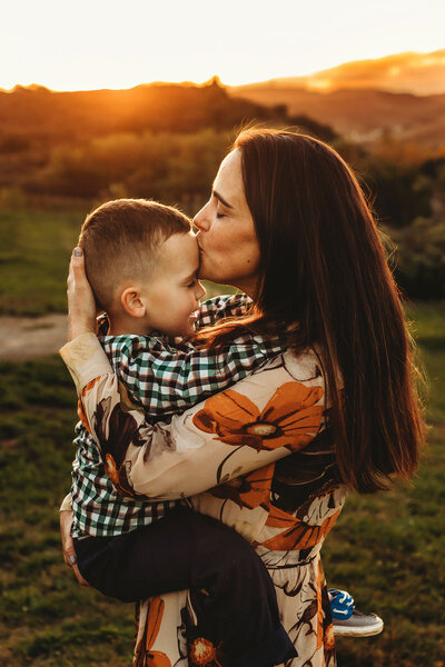 Mom holding son and kissing his forehead at sunset in Fort Collilns.