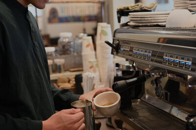 Man steams milk and prepares to pour latte at Hillcrest Coffee