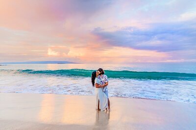 Couple holds eachother on the beach under a pastel sunrise sky in Wailea, Maui during proposal photoshoot at the beach