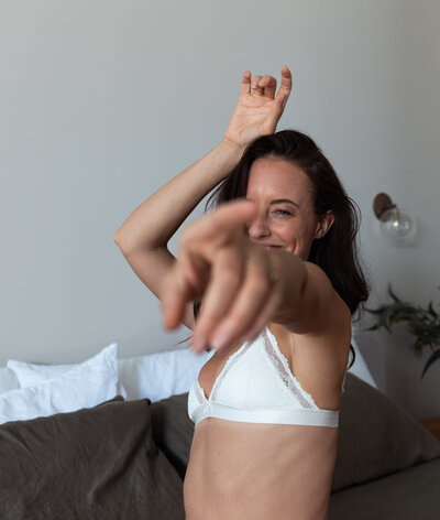 Meg pointing to the camera while sitting on a bed