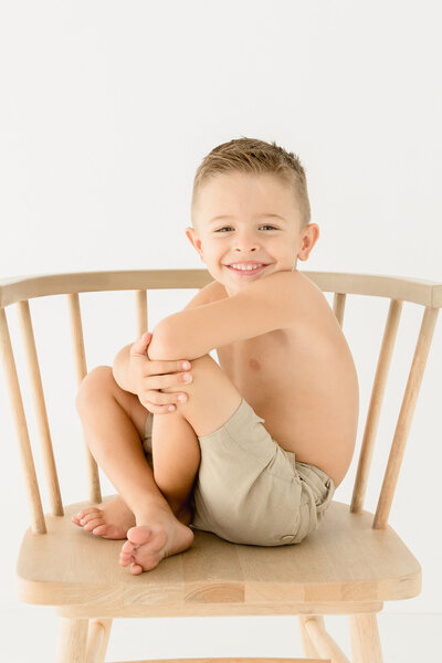 Little boy sitting on a chair for his 5th birthday portrait