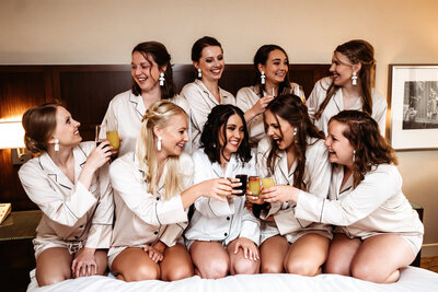 Bride and bridesmaids in robs cheering with their mimosas
