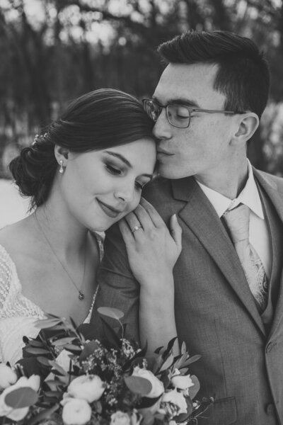 Black and white photo of groom kissing bride on forehead by Iowa City wedding photographer Sabrina Wilham