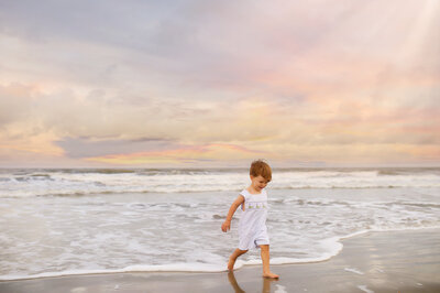 Toddler playToddler plays on the beach during  Family Photos on the Beach in Charleston, South Carolina.