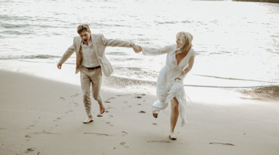 Newlywed couple running on the beach.