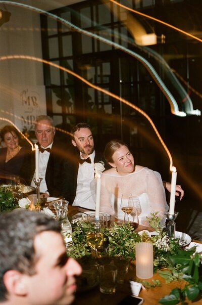 image shot by tom thornton photography of minnesota wedding guests at banquet table reception look to the side with light painting by candles