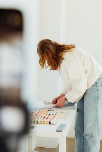 Interior designer Erin Lima looks at design materials including swatches, representing interior design coaching.