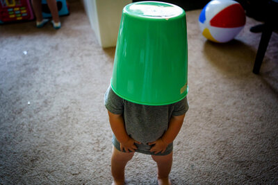 toddler boy with green bucket on his hand and now pants - unposed family photographer