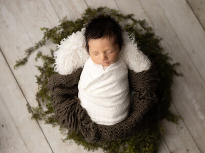 newborn baby boy wrapped in white for studio portrait