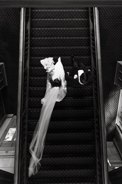 Artistic black and white bridal portrait on escalator with flowing veil
