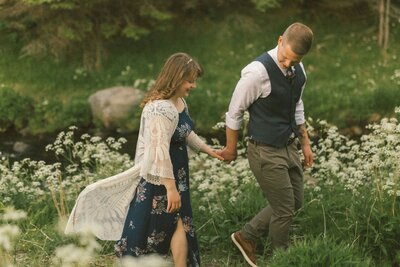groom leads bride through a field of wildflowers
