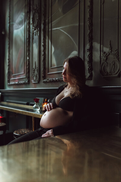 Zwangerschapsfoto van een vrouw met hand op haar buik in moody sfeer